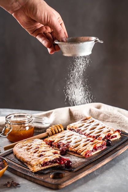 Le chef saupoudre le sucre glace sur une tarte sucrée avec des baies