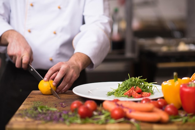 Photo chef servant une salade de légumes sur une assiette dans la cuisine du restaurant