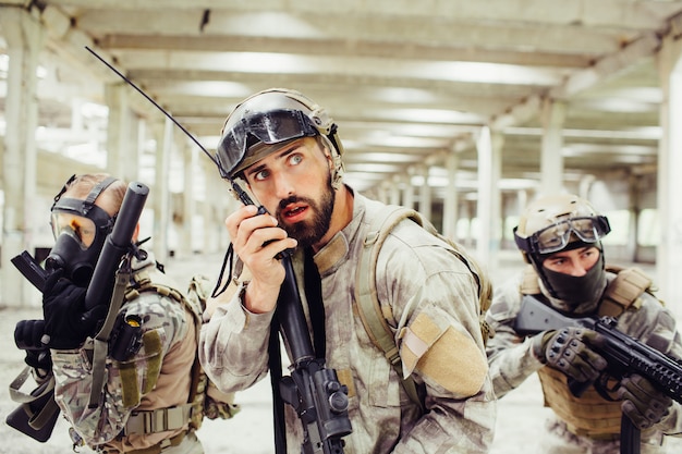 Le chef des soldats tient le fusil dans les mains et parle à une radio portable.