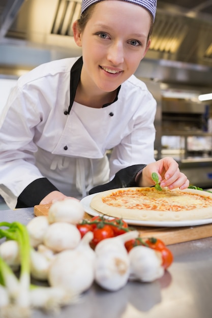 Chef souriant décorer la pizza