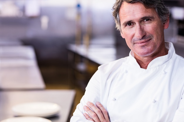 Chef souriant avec les mains croisées dans la cuisine