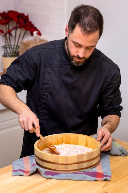 Le chef de sushi professionnel prépare le riz dans un bol en bois en faisant attention au produit