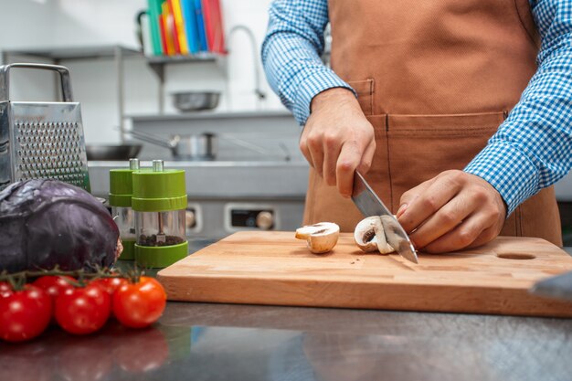 Le chef en tablier marron faisant la cuisine dans un restaurant