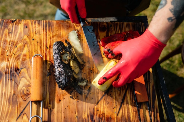 Chef tatoué avec des gants en caoutchouc hacher des légumes à l'extérieur Concept de grill party