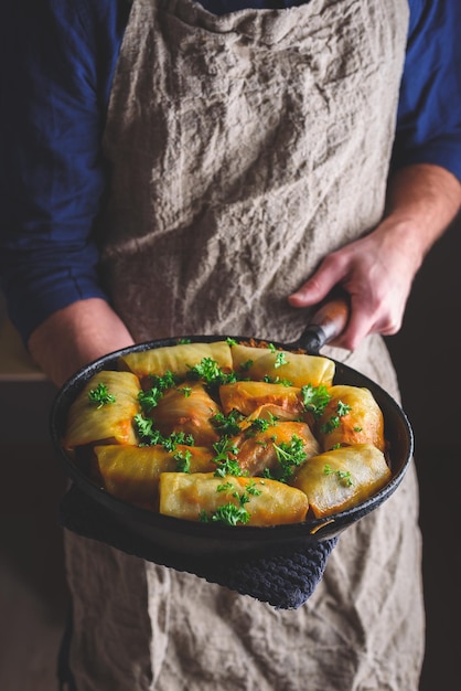 Chef tenant une casserole avec des rouleaux de chou cuits