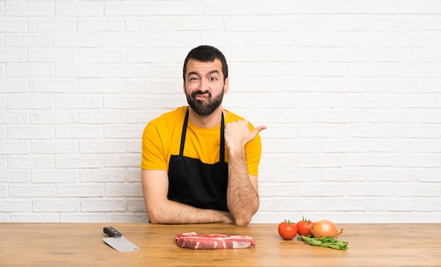 Chef tenant dans une cuisine malheureuse et pointant sur le côté