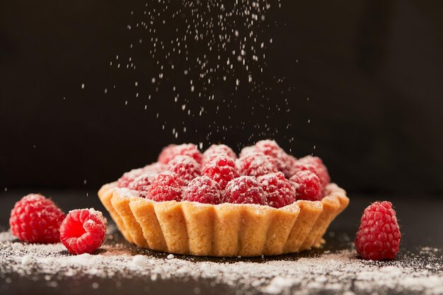 Chef tenant une tarte aux framboises au café