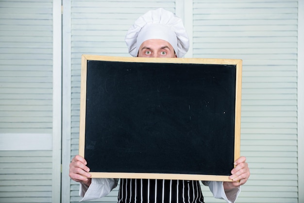 Le chef tient l'espace de copie du tableau noir cache le visage derrière le concept de recette Cuisiner un délicieux repas étape par étape Menu pour aujourd'hui Liste des ingrédients pour le plat de cuisson Conseils pour cuisiner comme un pro Découvrez les conseils de cuisine