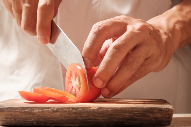 Chef de tomates coupées sur planche à découper avec couteau