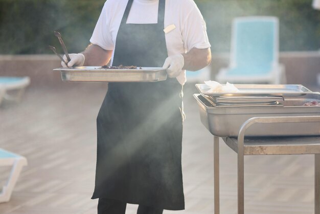 Le chef transporte des plats cuisinés en métal pour faire frire des aliments faire un pique-nique à l'extérieur