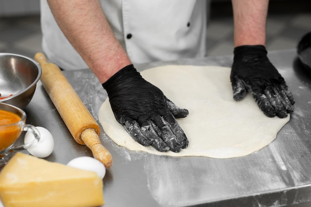 Le chef travaille dans la cuisine avec de la pâte à pizza