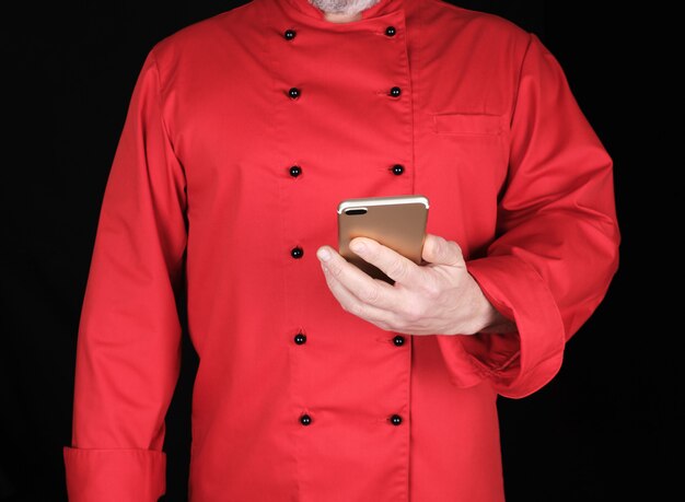 Chef en uniforme rouge tient dans sa main un smartphone