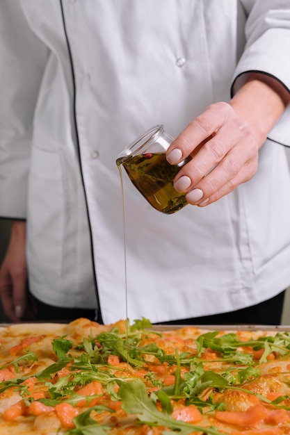 Chef versant de l'huile d'olive sur la pizza