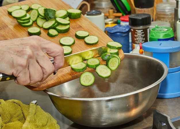 Le chef verse des courgettes dans un saladier dans la cuisine