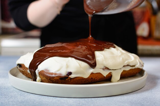 Photo le chef verse du glaçage au chocolat sur le gâteau fini