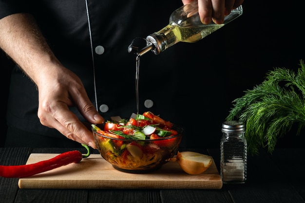 Le chef verse l'huile d'olive dans un bol de salade