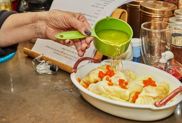 Le chef verse de la sauce sur des rouleaux de chou avec des carottes de saumon dans la recette française de la cuisine