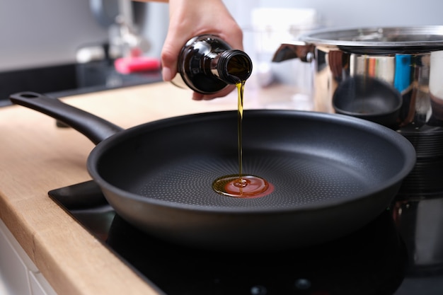 Chef verser de l'huile d'olive dans une poêle en gros plan de la cuisine