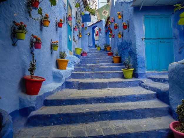 Photo chefchaouen la ville bleue au maroc avec des pots colorés décorant une cage d'escalier bleue