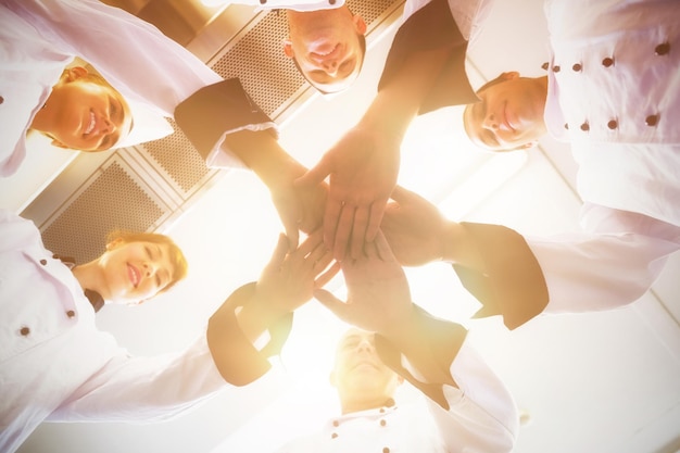 Chefs joignant les mains en cercle portant des uniformes dans une cuisine