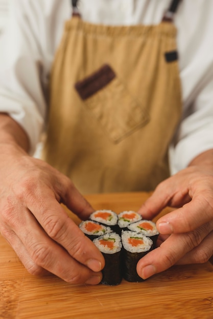 Chefs mâles faisant des rouleaux de sushi avec du poisson saumon et des légumes