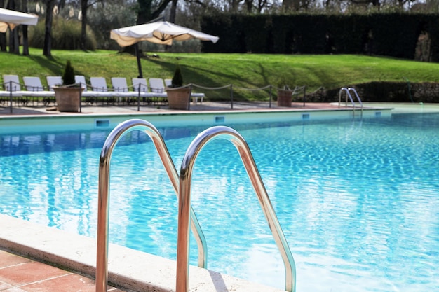 Échelle en chrome brillant dans la piscine avec de l'eau bleue