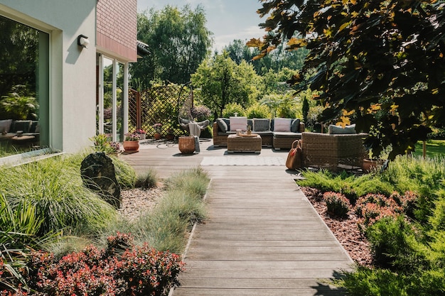 Chemin en bois menant à la terrasse dans le jardin avec des meubles de jardin à la mode