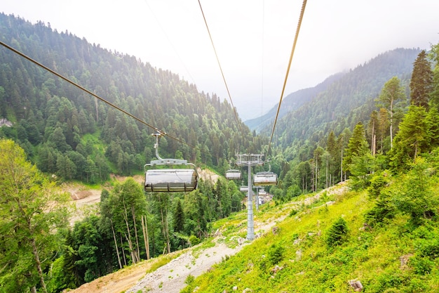 Photo chemin du téléphérique dans les montagnes sur la pente du pic dans la vue en perspective de la forêt d'été
