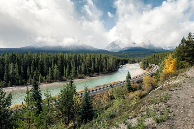 Chemin de fer avec des montagnes rocheuses et nuageux dans la vallée d'automne à Morant's Curve, Calgary, Canada