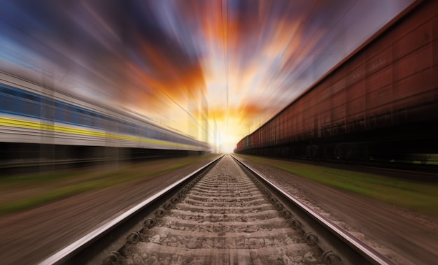Chemin de fer en mouvement au coucher du soleil avec un ciel dramatique. Effet de flou de mouvement.