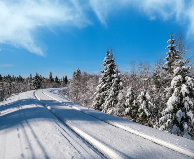 Chemin de fer à travers une forêt de sapins enneigée et un casque alpin isolé dans les montagnes des Carpates