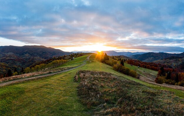 Chemin menant au sommet de la montagne à travers le pré au lever du soleil