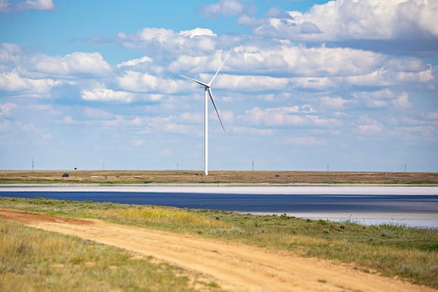 Un chemin de terre avec un chemin de terre et une éolienne au loin.