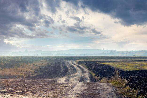 Chemin de terre dans le champ en automne un jour nuageux ciel pluvieux foncé au-dessus du champ