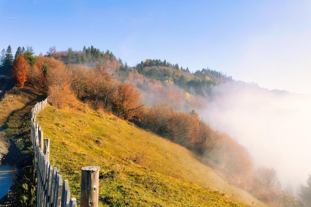 Un chemin de terre dans les montagnes entouré d'une vieille clôture en bois