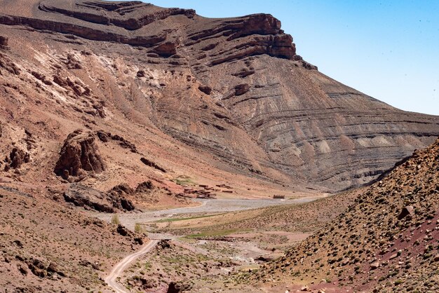 Un chemin de terre descend dans la profonde vallée déserte du Dadès dans les montagnes de l'Atlas au Maroc
