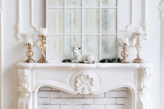 Cheminée blanche avec bougies et décorations de Noël. Intérieur classique.