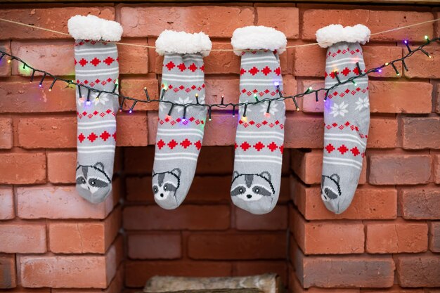 cheminée de briques décorées avec des chaussettes grises et des lumières de Noël