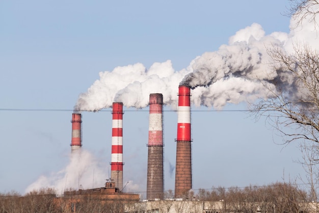 Photo les cheminées industrielles avec une épaisse fumée sur fond de ciel bleu. cheminée pollution dans l'air comme problème environnemental