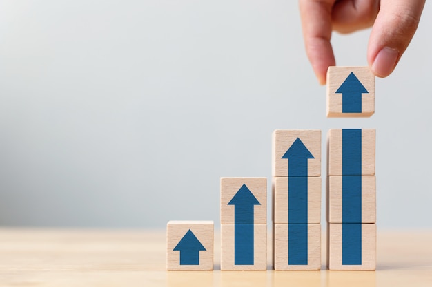 Cheminement de carrière en échelle pour le concept de processus de réussite de croissance d'entreprise. Arranger la main empiler des blocs de bois comme escalier avec flèche vers le haut