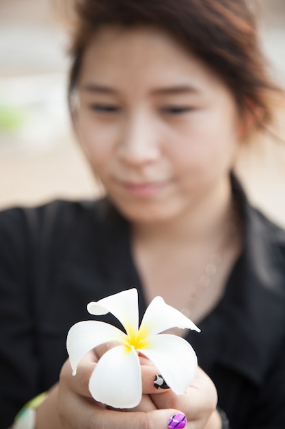 Chemise noire des femmes asiatiques. Tenant une fleur blanche.