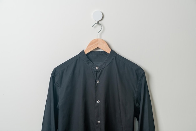 chemise noire suspendue avec cintre en bois au mur