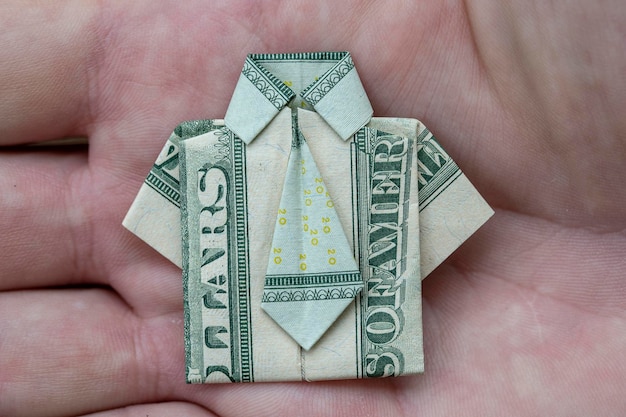 Chemise origami faite de billets de banque en dollars sur fond de main Closeup Dollar bill Tshirt