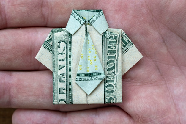 Chemise origami faite de billets en dollars sur fond de main. Fermer. T-shirt billet d'un dollar