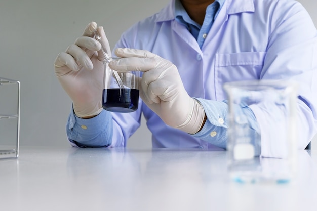 Photo le chercheur de laboratoire médical ou scientifique masculin effectue des tests avec du liquide bleu en laboratoire. concept d'expériences de science de l'équipement.