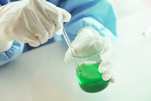 Un chercheur en laboratoire scientifique effectue des tests avec un liquide vert. Fermer