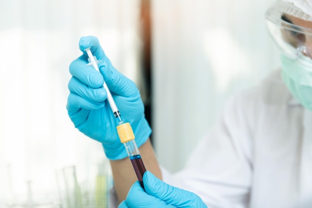 Le chercheur ou les scientifiques chargent le liquide dans l'échantillon de sang dans le tube à essai