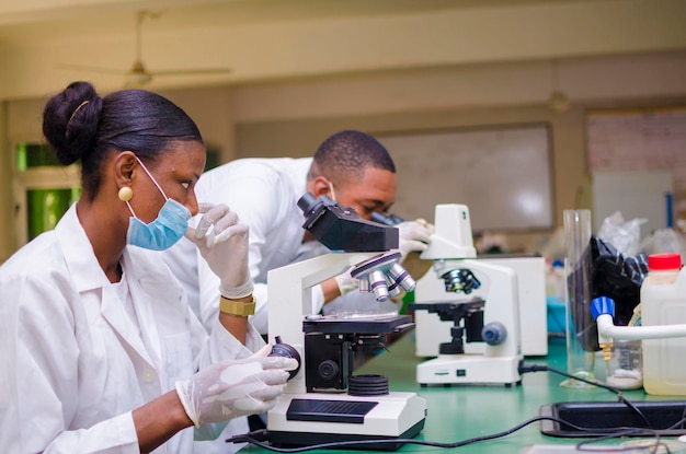 Chercheurs africains en soins de santé travaillant dans un laboratoire des sciences de la vie. jeune chercheuse scientifique et superviseur masculin principal préparant et analysant des lames de microscope dans le laboratoire de recherche