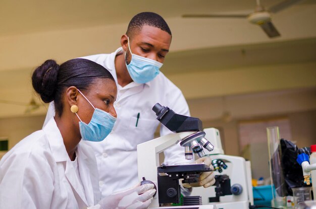 Chercheurs africains en soins de santé travaillant dans un laboratoire des sciences de la vie. jeune chercheuse scientifique et superviseur masculin principal préparant et analysant des lames de microscope dans le laboratoire de recherche