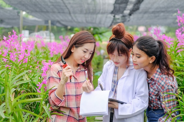 Des chercheurs, de jeunes femmes vêtues de robes blanches et des propriétaires de jardin d’orchidées collaborent